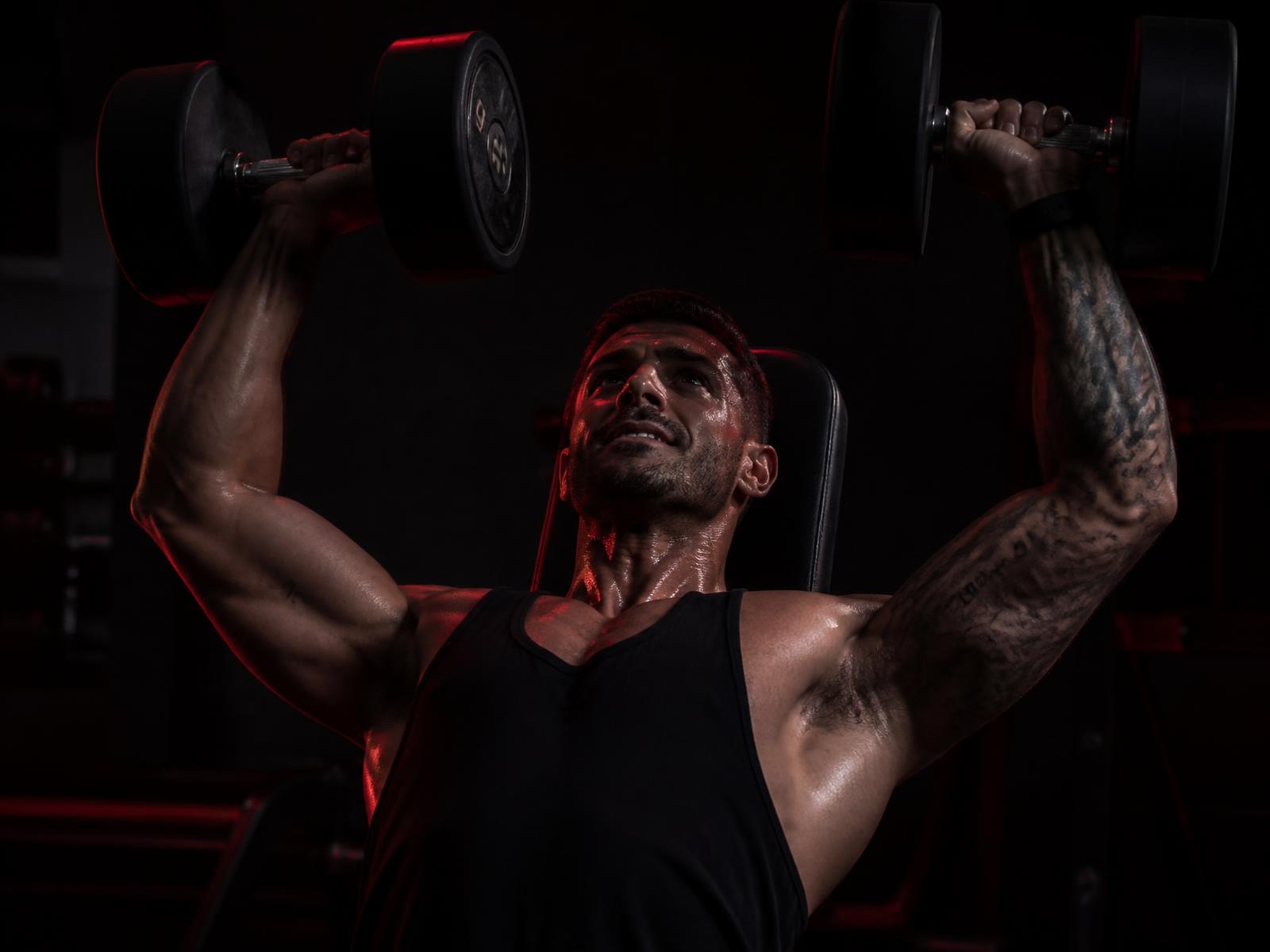 Coach training with dumbbells under red gym lighting